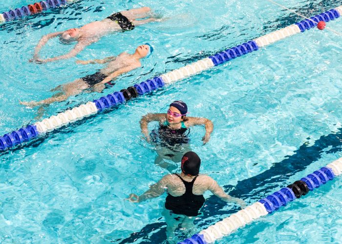 Dzieci ćwiczą pływanie różnymi stylami w basenie